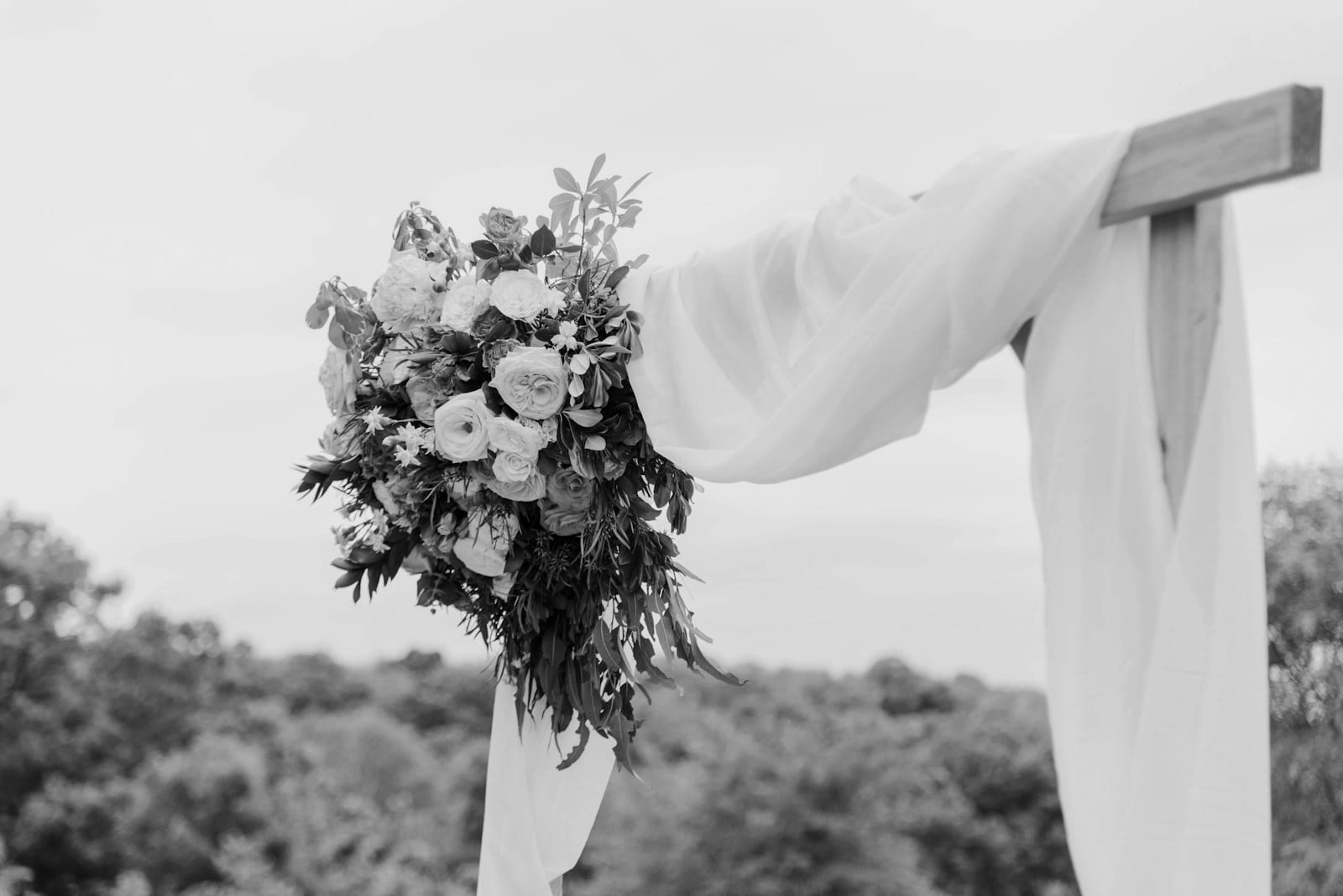 Floral bouquet on draped fabric at a ceremony arch